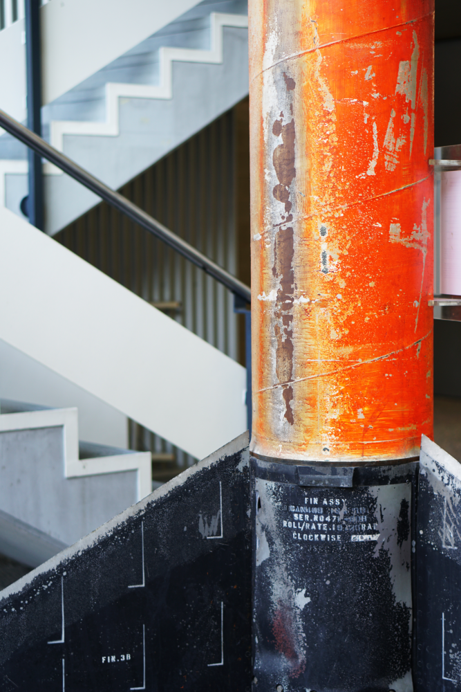 Ausschnitt einer Rakete, unten sieht man in Schwarz die Flossen und darüber in Rot den Rumpf.