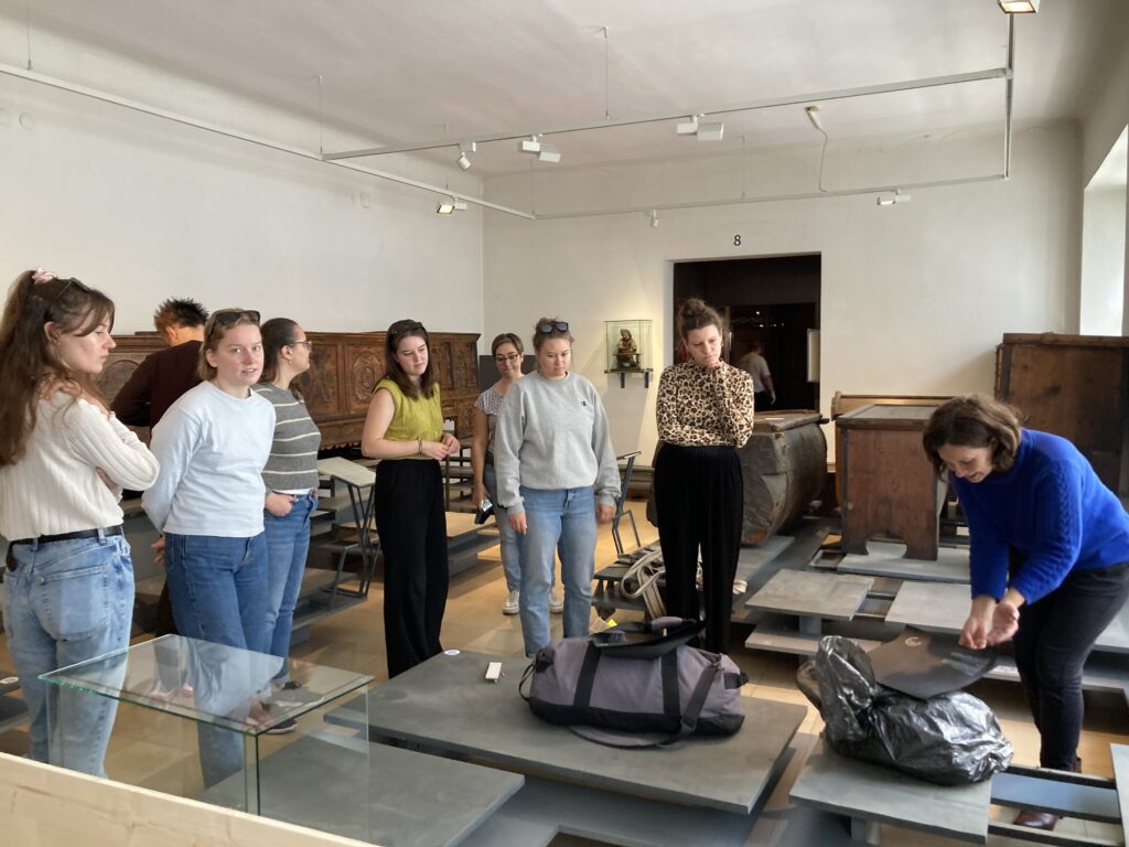 Menschengruppe in einem Museumsraum mit unterschiedlichen Exponaten