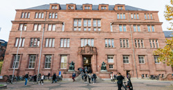 College Building I of the University of Freiburg, a three-storey red sandstone building, people in the foreground