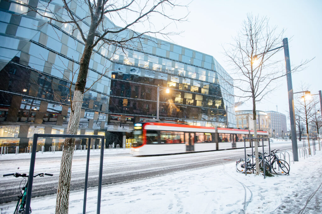 A tram quickly passes the university library. There is snow