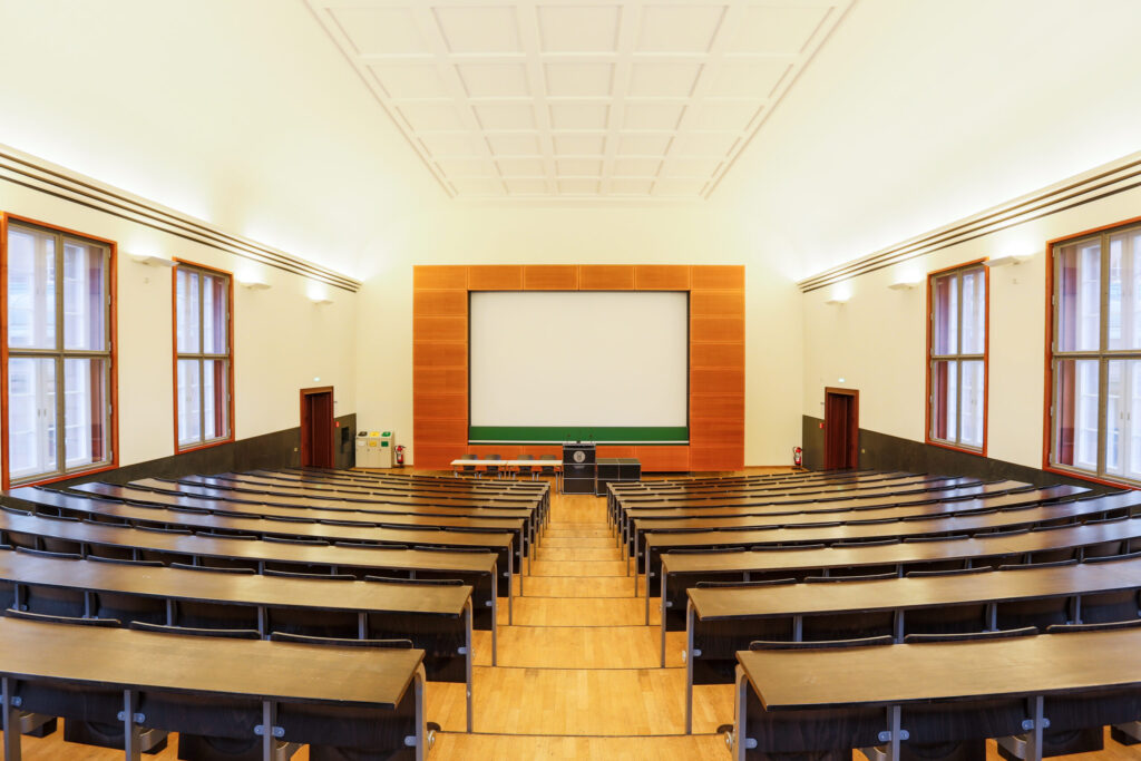 View into an empty lecture hall with wooden seats and benches.