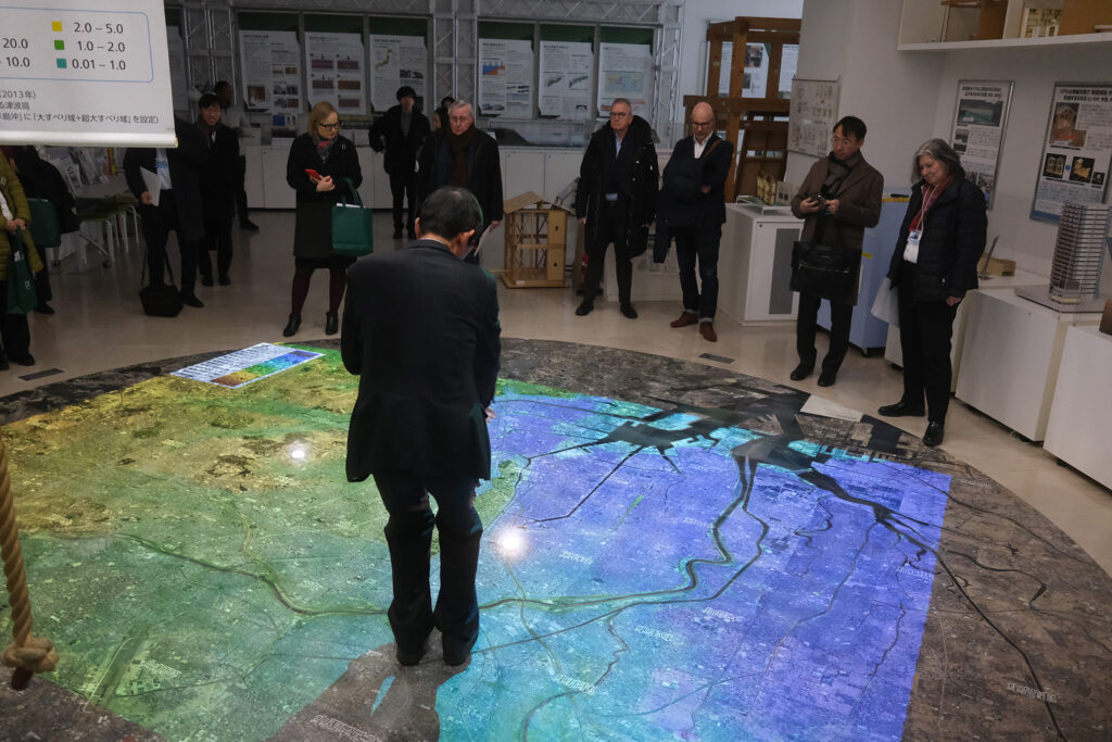 Several people look at a projection on the floor.