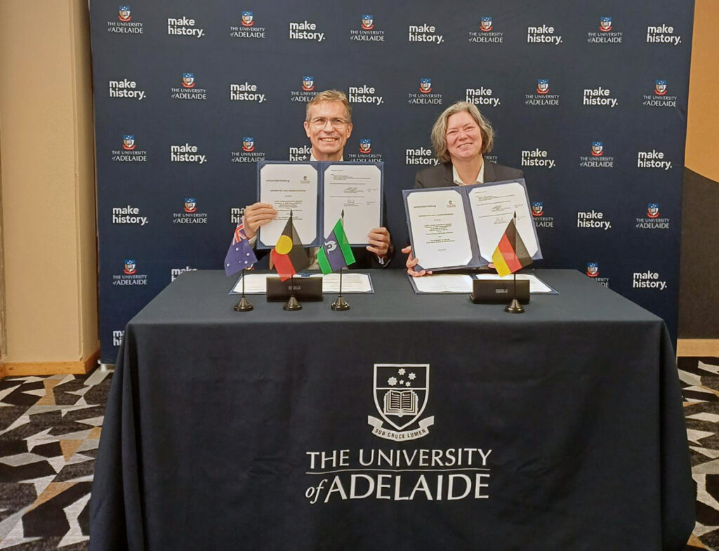 Two people present signed documents.