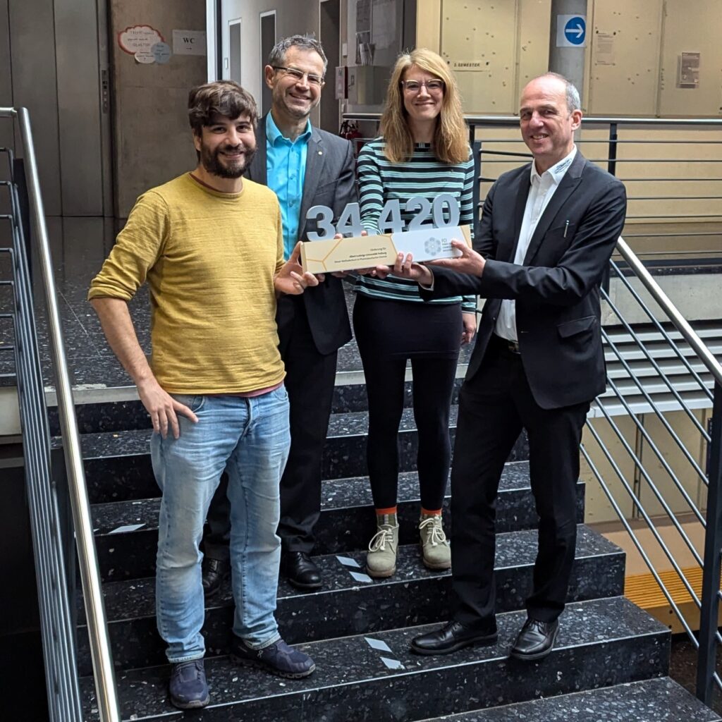 Four persons on a stair holding a prize.