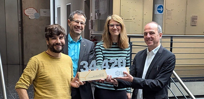 Four persons on a stair holding a prize.