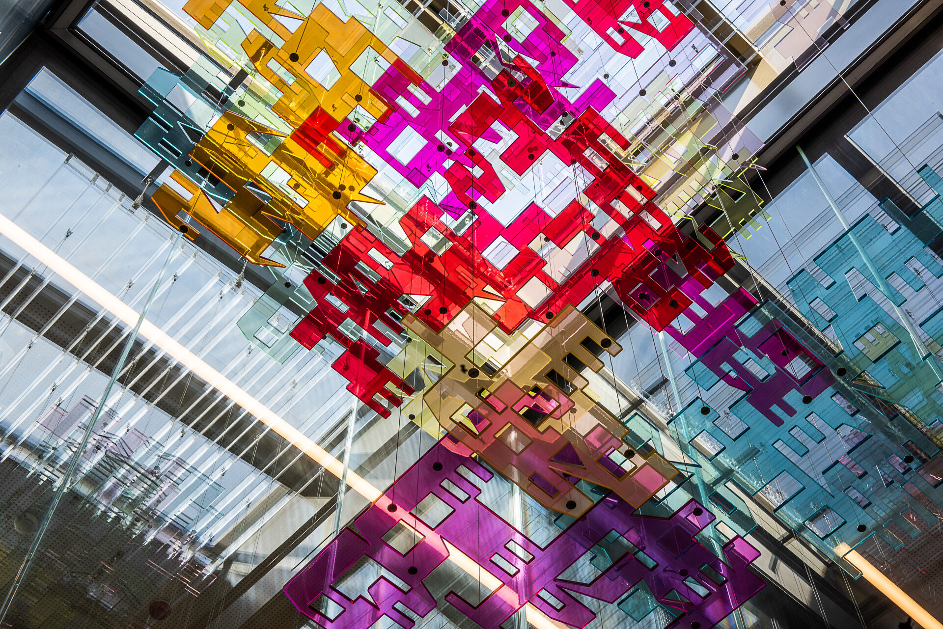 A glass roof from which hangs a colorful art installation.