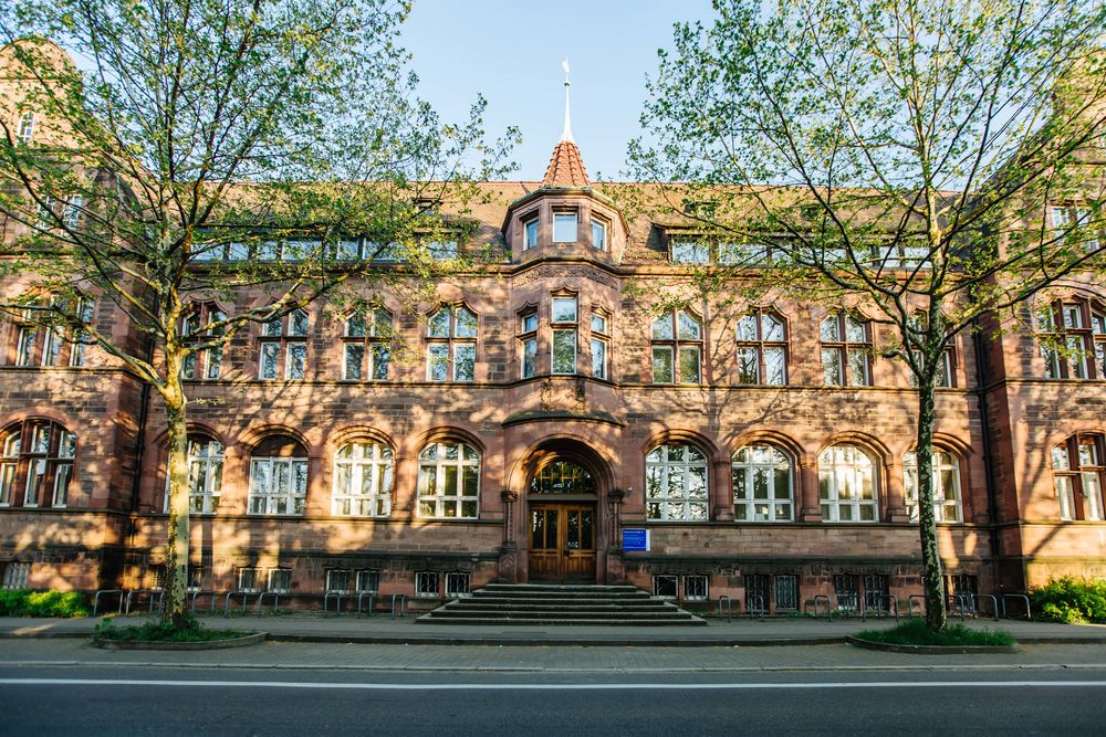 Westfassade des Institutsgebäudes der mediznischen Fakultät an der Stefan-Meier-Straße hinter Bäumen.