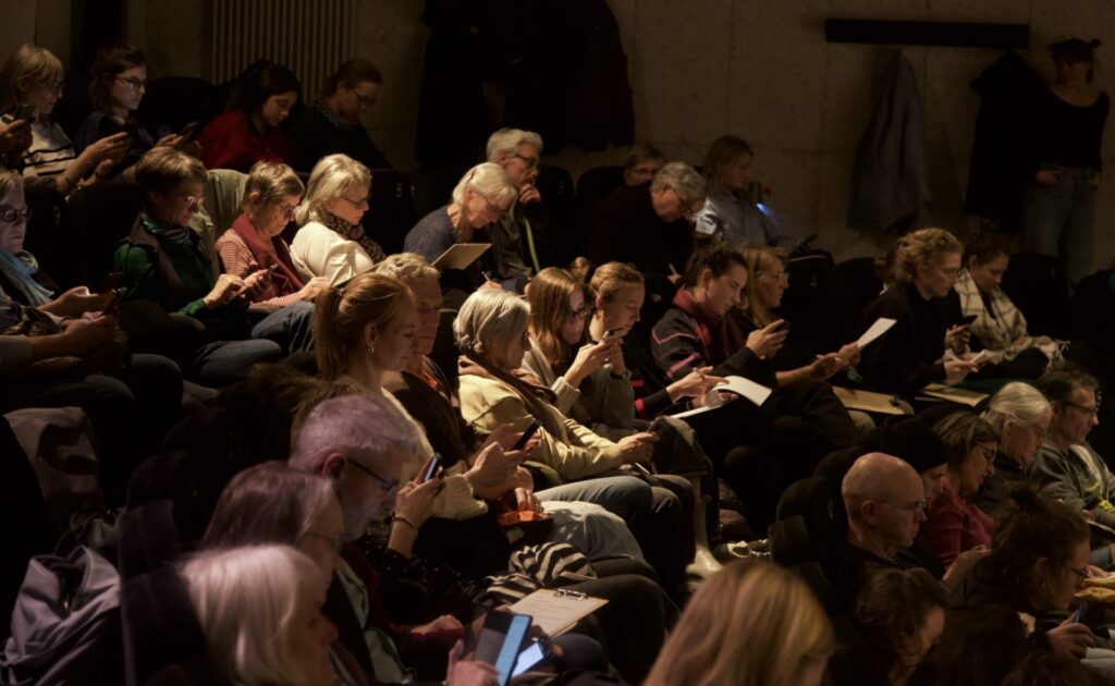 Participants in the film series of the “Visions of Sustainability” project of the Innovation Campus at the Harmonie cinema fill out questionnaires for the research.