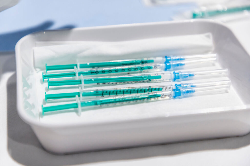 Vaccination syringes lie in a bowl