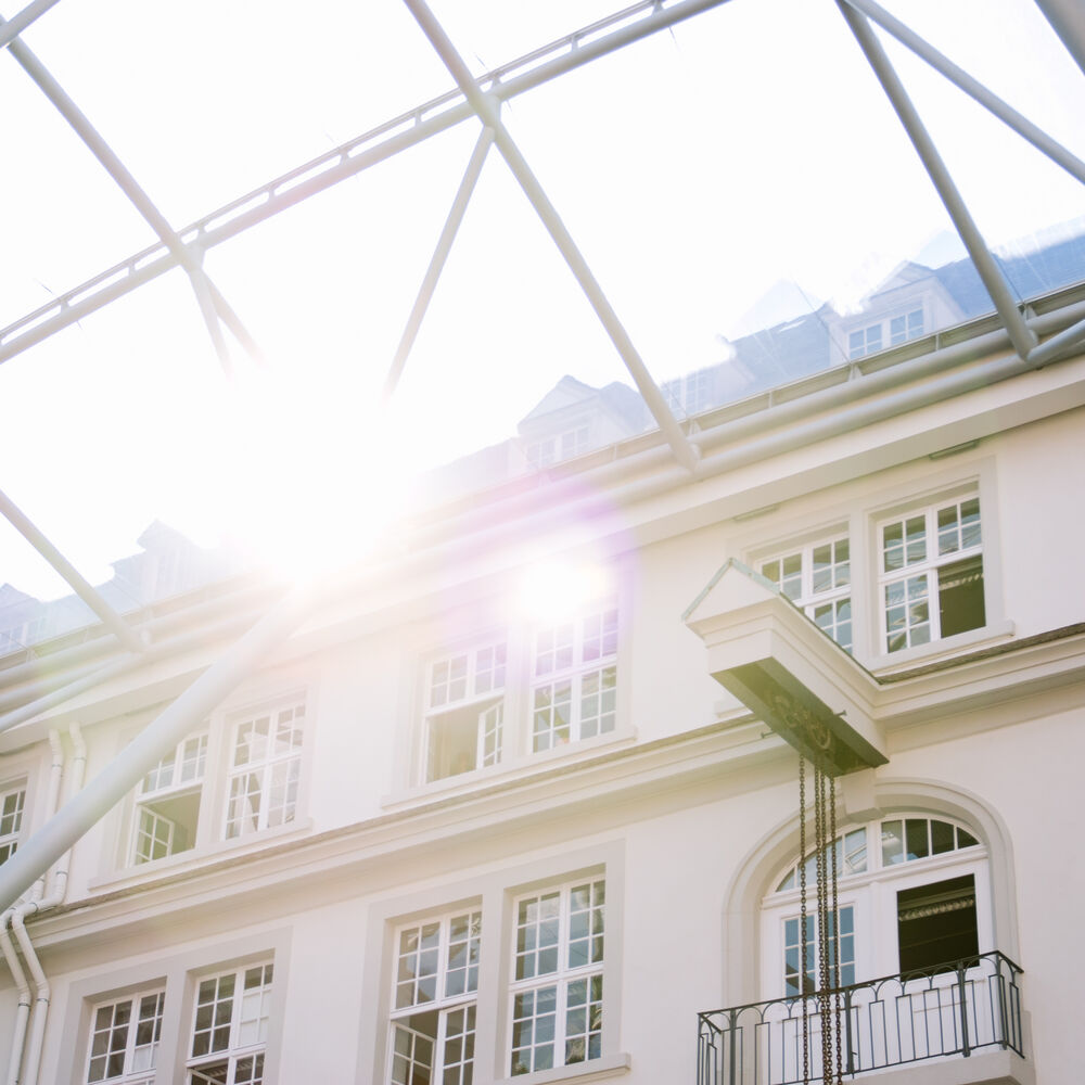 Sonnenschein fällt auf ein Fenster einer Hausfassade in einem Innenhof der Universität Freiburg.