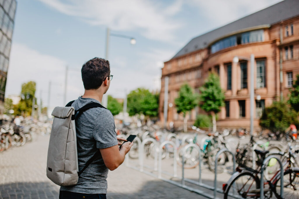 Studierender mit Smartphone orientiert sich vor dem Kollegiengebäude  I.