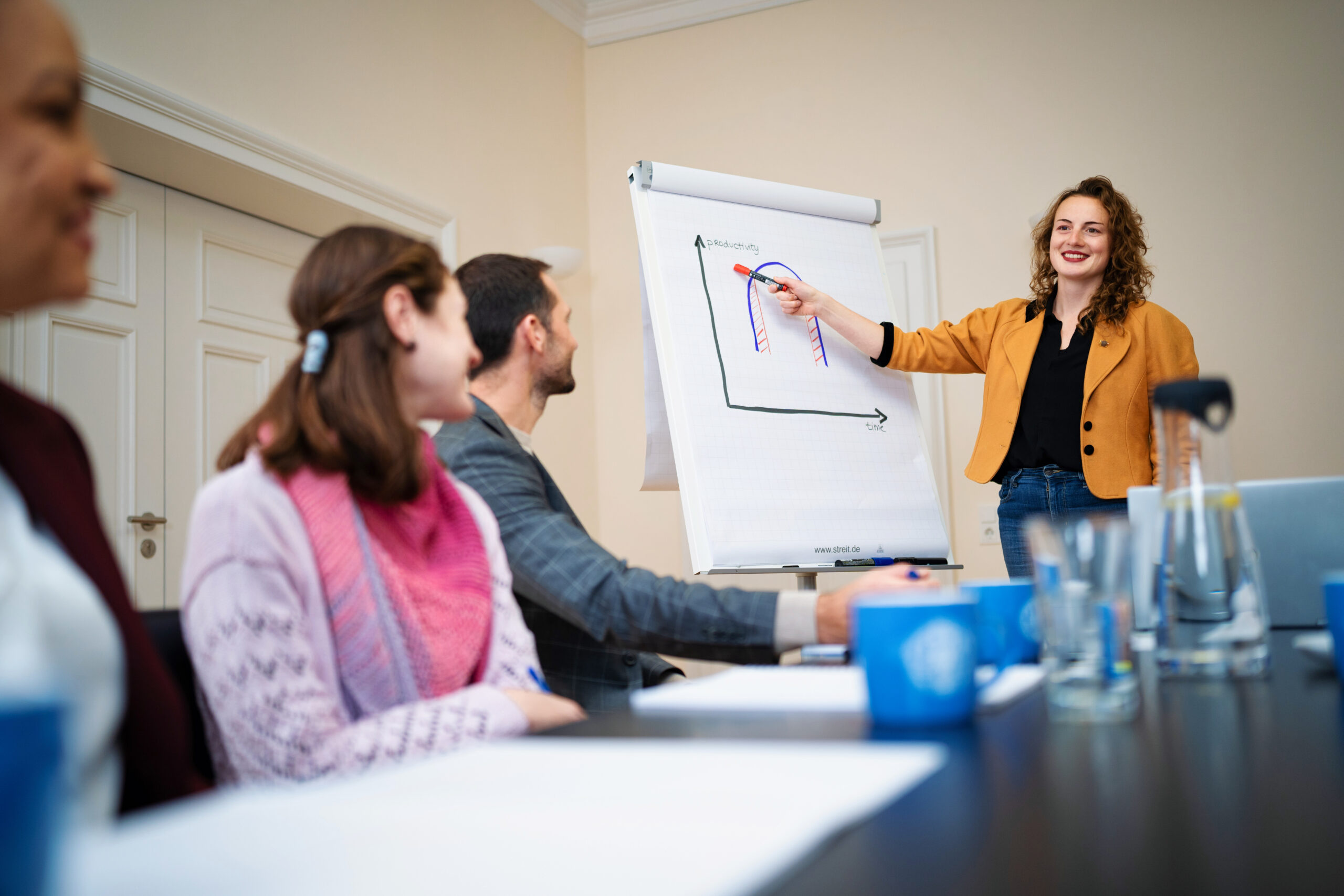 A woman shows something on a whiteboard while workshop participants listen to her.