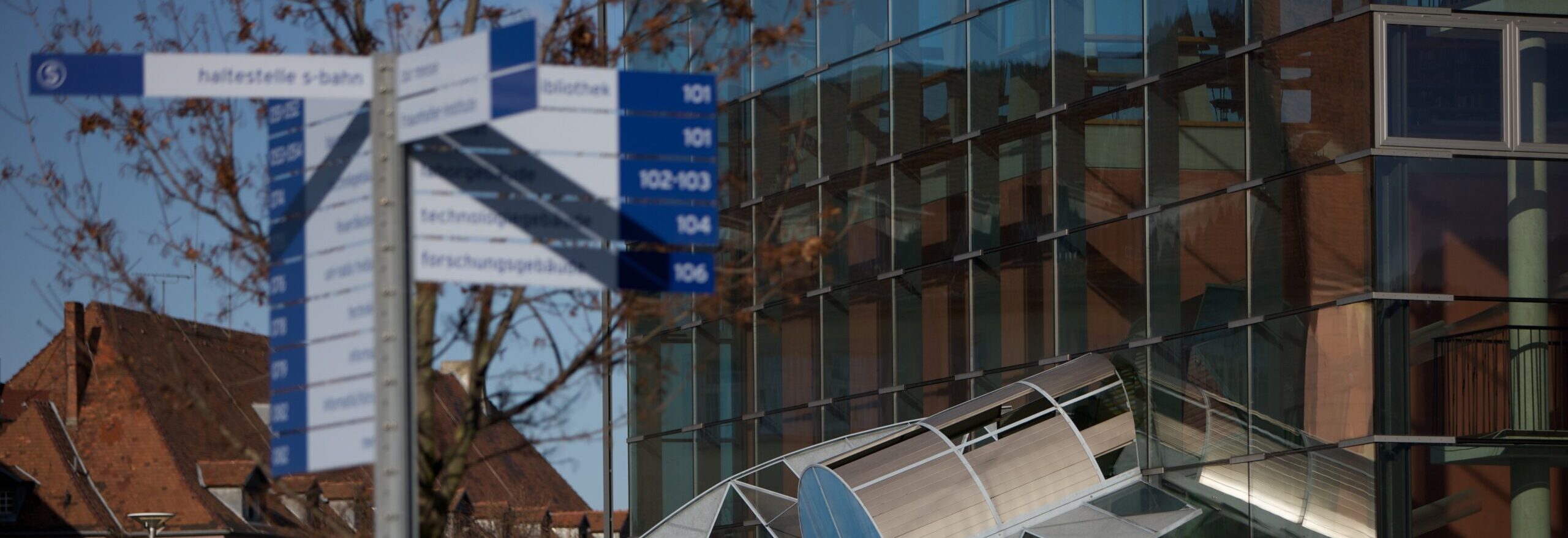 Modern building on the grounds of the Faculty of Engineering. In the foreground, a signpost pointing the way in various directions.