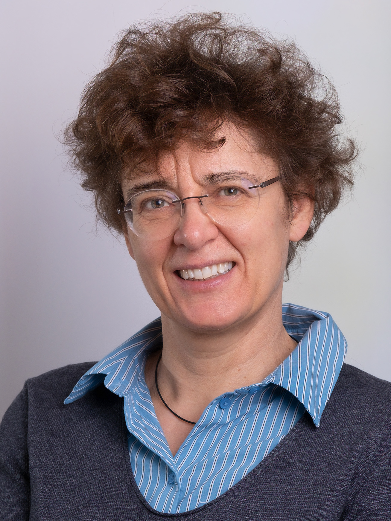 portrait of Prof. Tanja Vogel, a white colored woman with brown curly hair and glasses, she smiles friendly.