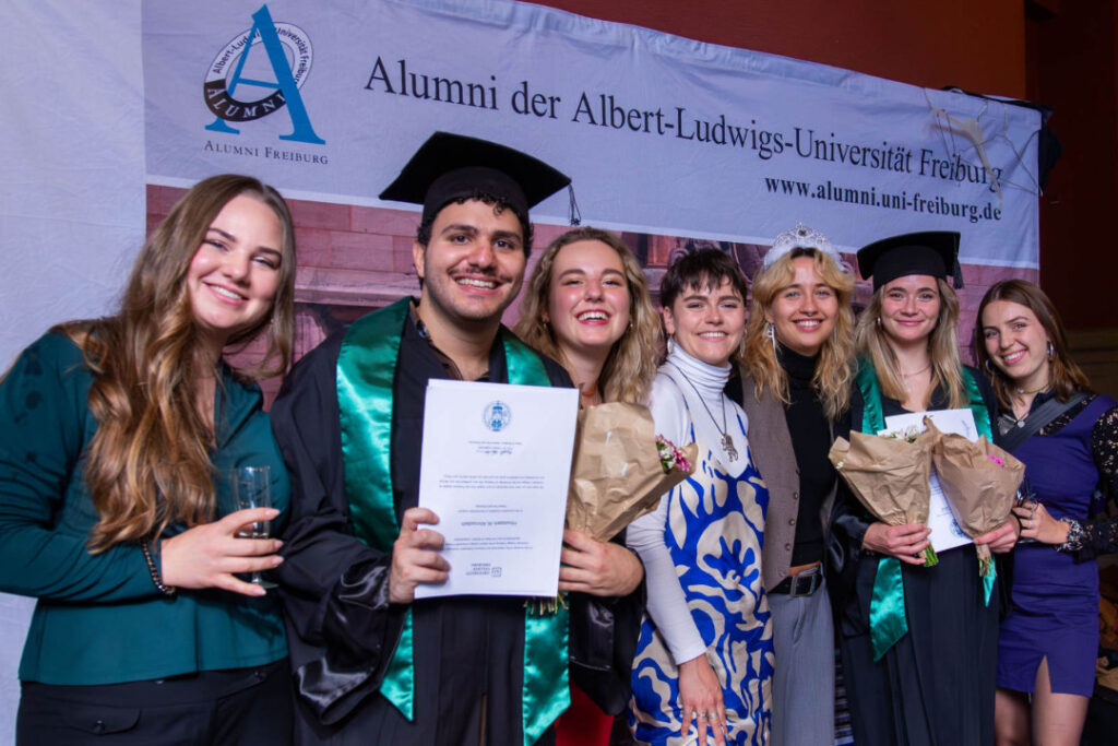 Graduates and peers posing with diplomas and flowers.