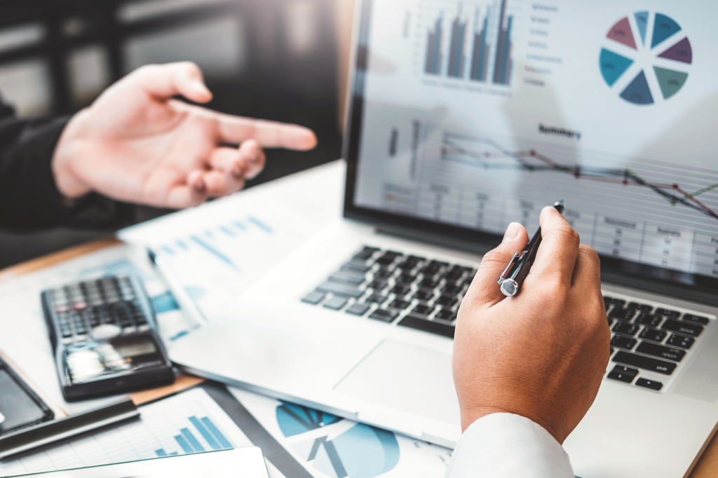 Hände zweier Personen vor einem geöffneten Laptop, der Diagramme zeigt.