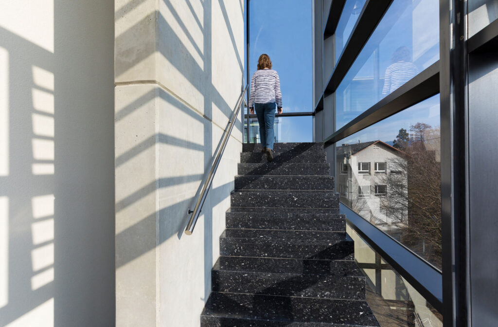 Eine Person steigt eine Treppe in einem modernen Bürogebäude hinauf.