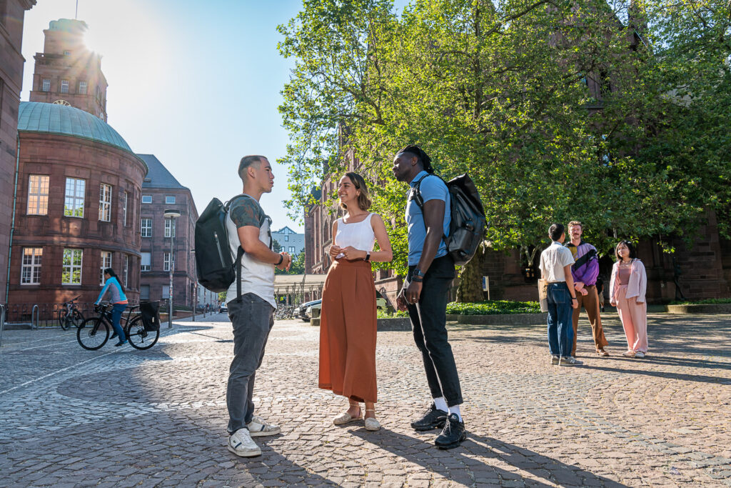 Studierende der Universität Freiburg unterhalten sich auf dem Platz der Universität.