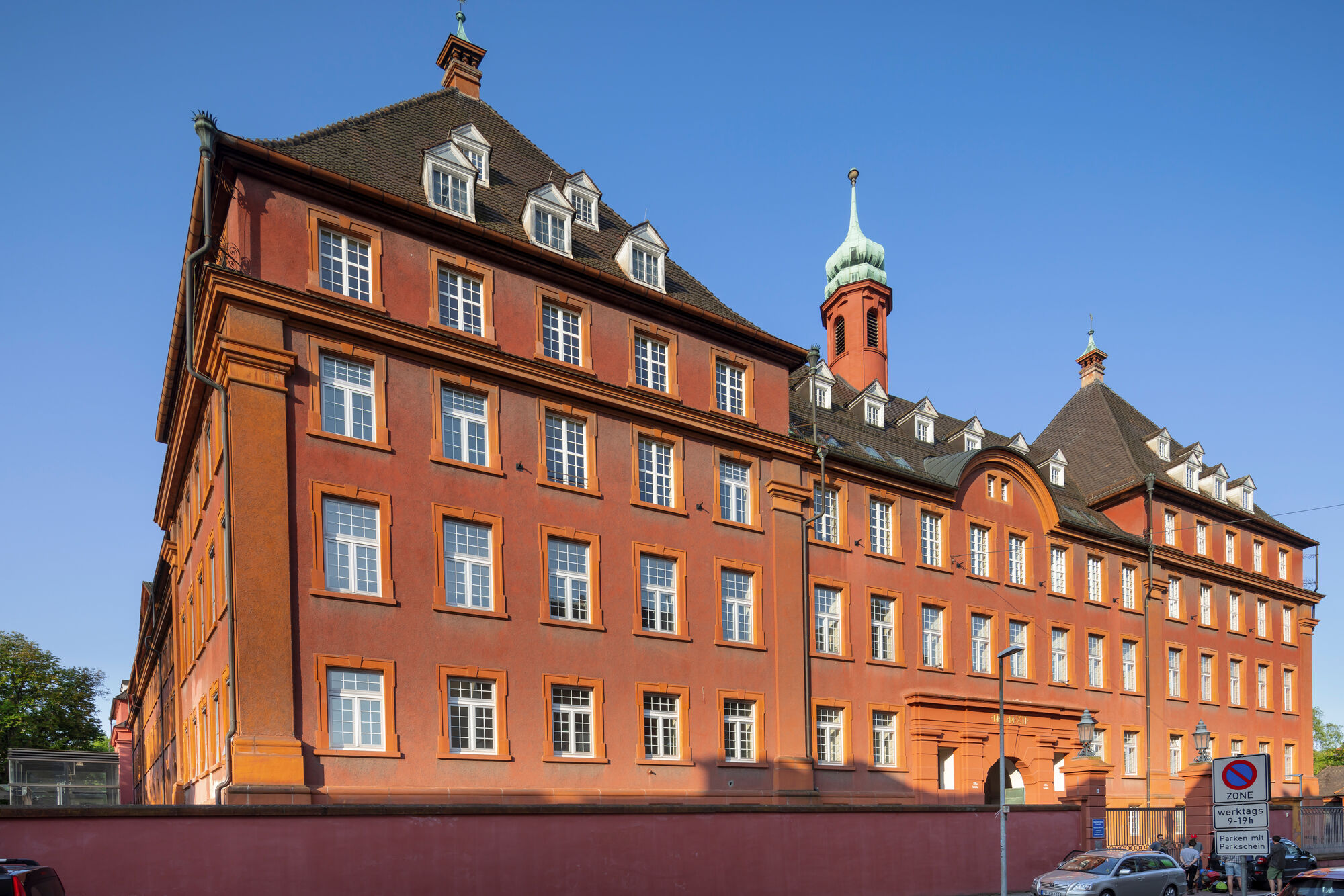 Ein rotes, großes Gebäude vor blaumem Himmel - Institut für Forstwissenschaften der Universität Freiburg.