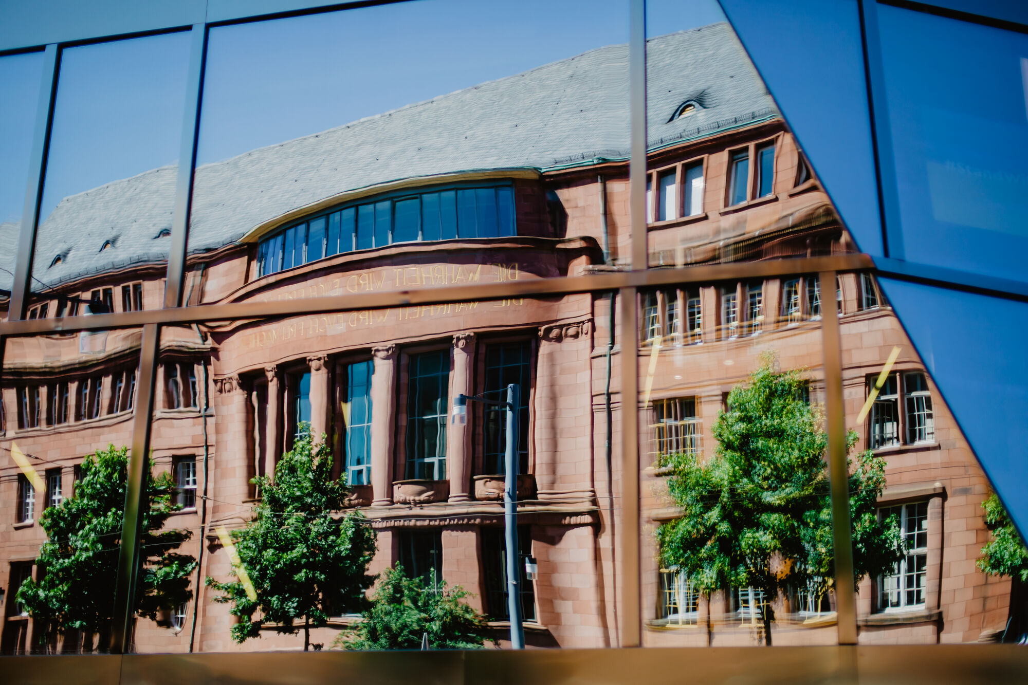 Spiegelung des Kollegiengebäudes I in der Fassade der Universitätsbibliothek Freiburg.