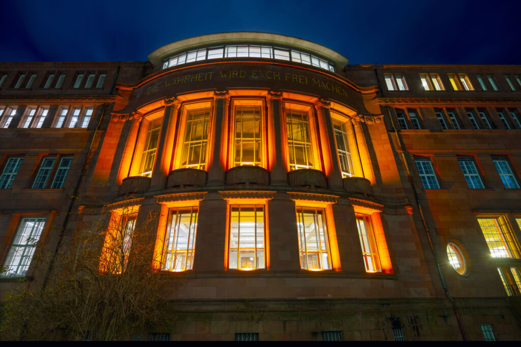 Ein mittelalterliches Gebäude leuchtet orange von innen heraus.