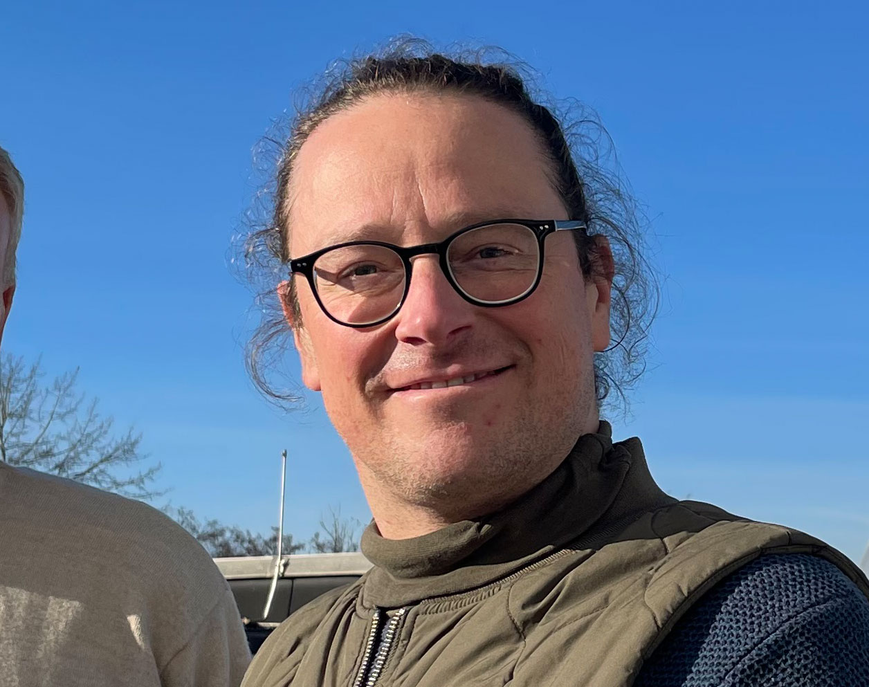 Ein Mann mit Brille und zusammengebunden Haaren