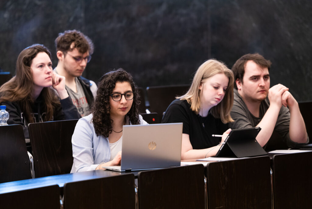 Junge Studierende sitzen konzentriert in einem Hösaal