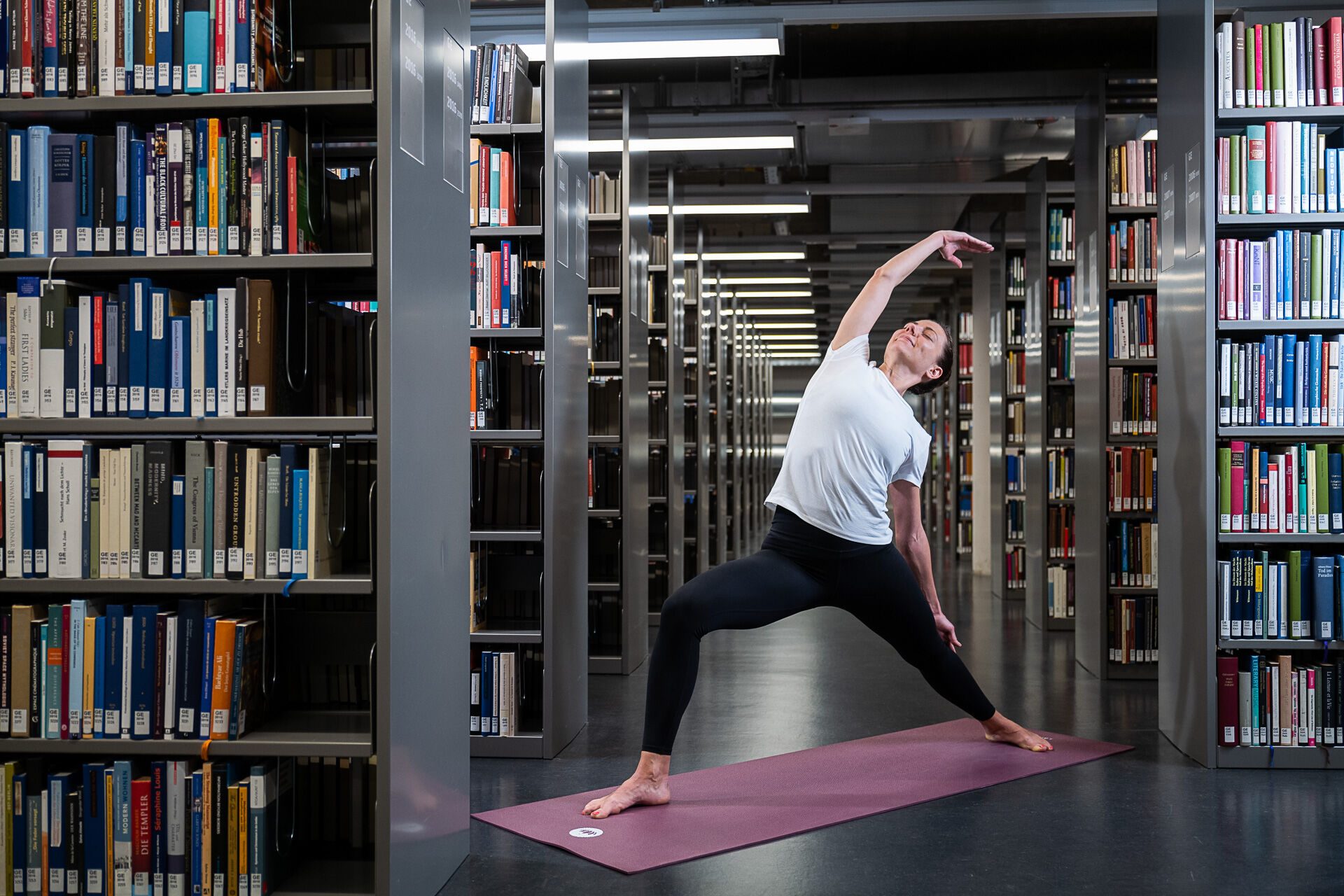 Eine junge Frau macht Yoga in der Universitätbibliothek Freiburg.