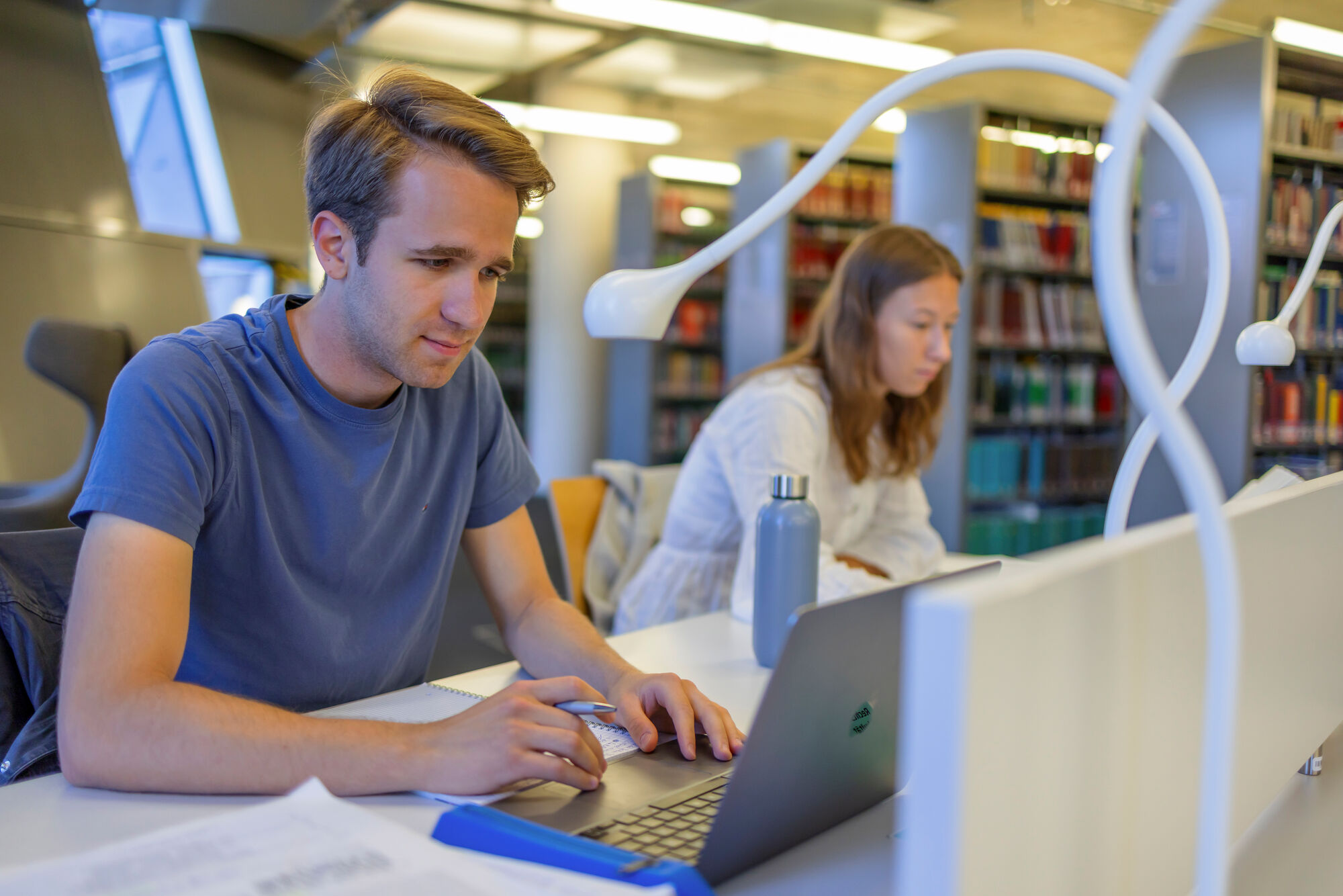 Zwei Studierende lernen mit ihren Laptops in der Universitätsbibliothek Freiburg.