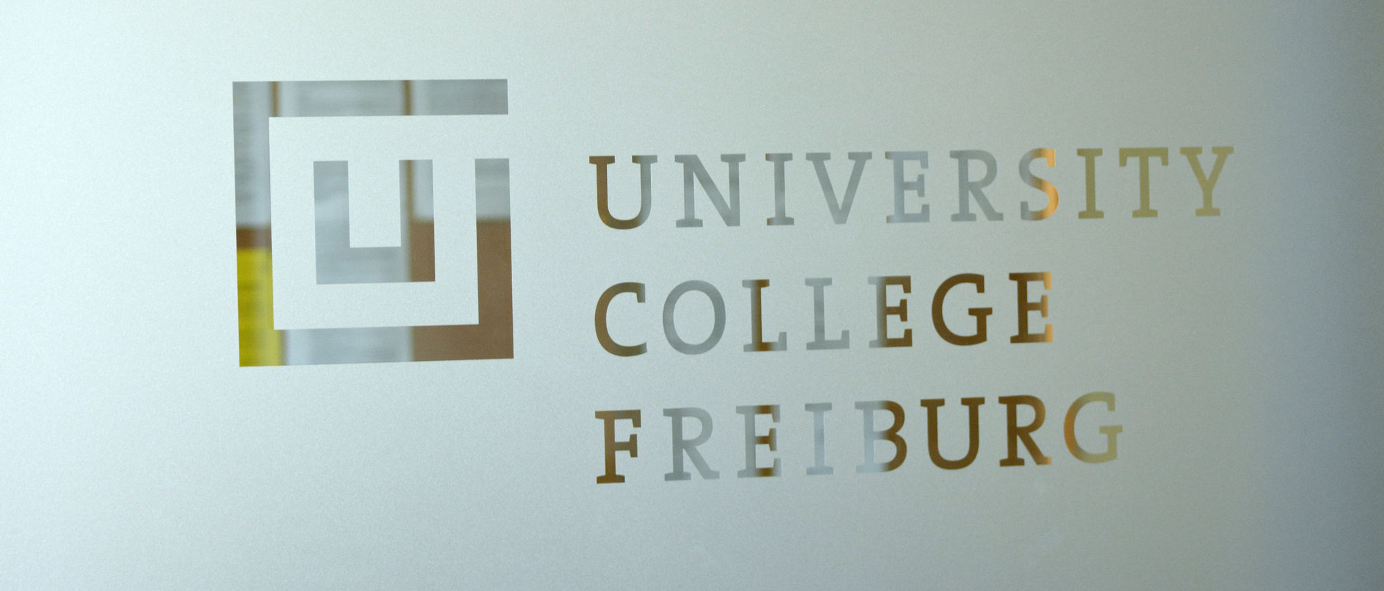 Auf mattem Glas aufgedrucktes Logo des University College Freiburg der Universität Freiburg.