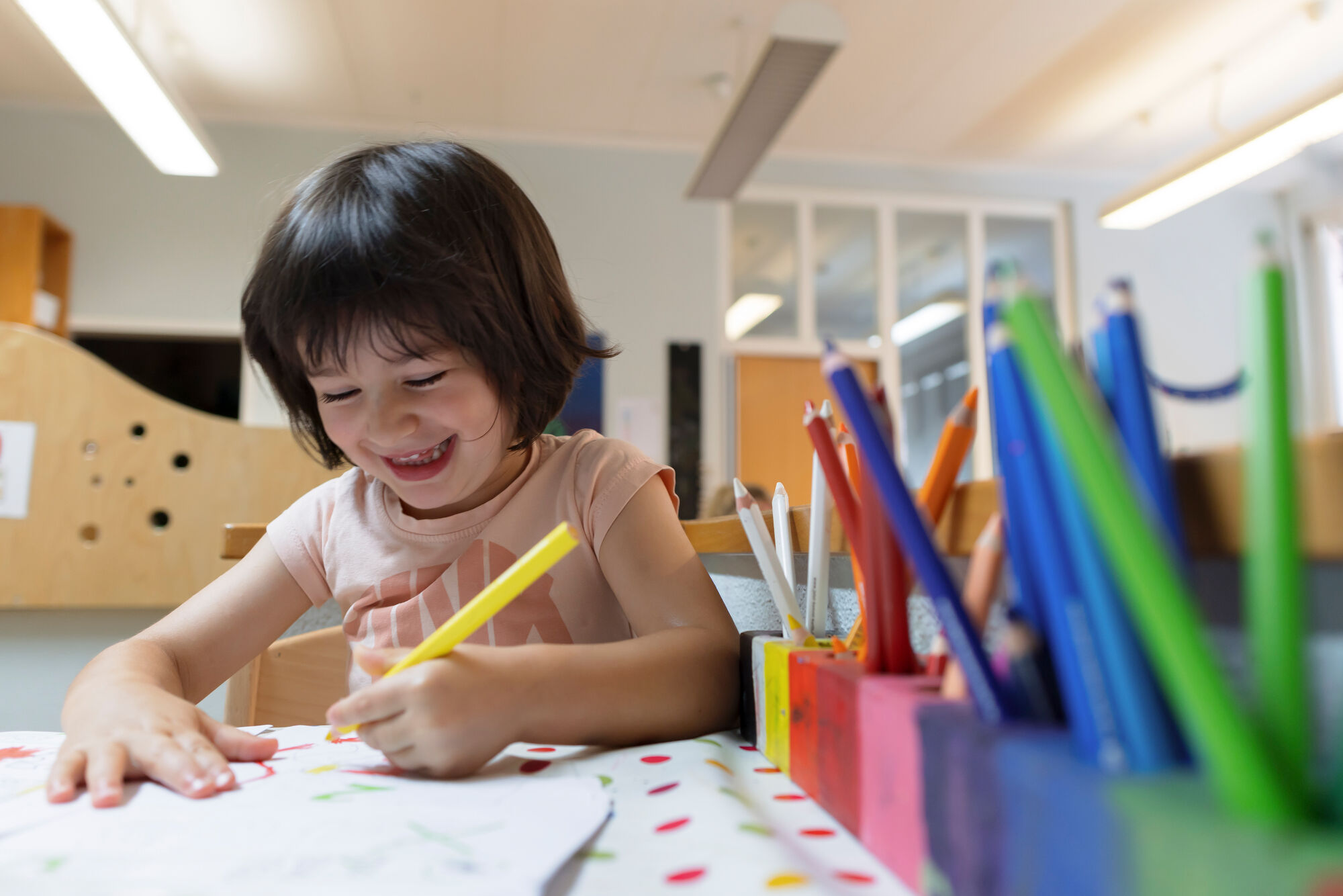 Ein lachendes Kind malt in der Kindertagesstätte der Universität Freiburg.