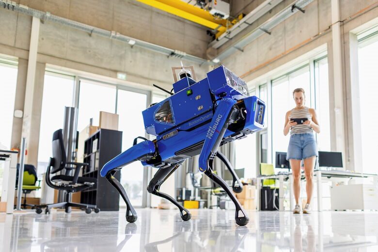 Eine Frau steuert einen blauen Roboter.