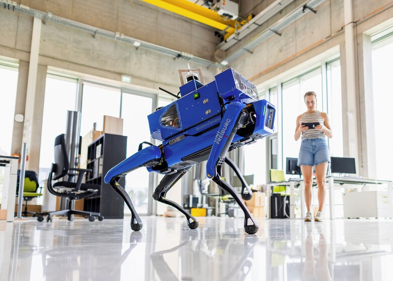 Eine Frau steuert einen blauen Roboter.