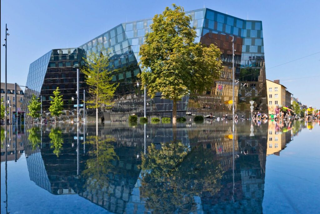 Das Gebäude der Universität Freiburg spiegelt sich in Wasser auf dem Boden.